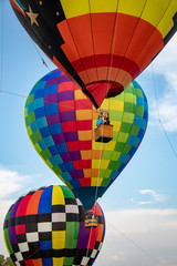 Brightly colored hot air balloons hover tethered above the ground while passengers enjoy the view...