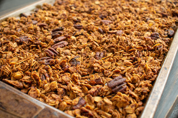 Freshly made cinnamon pecan granola on a sheet pan