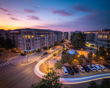 A car leaves a trail of light as it drives through the neighbourhood at sunset