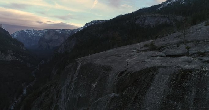 Aerial drone flight near running man on rock cliff at Yosemite National Park, 4k