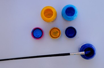 Opened paint bottles and brush on white background. Yellow and blue colors.  Art painting. 