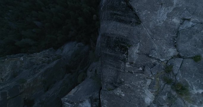 Aerial drone flight over running man on rock cliff at Yosemite National Park, 4k