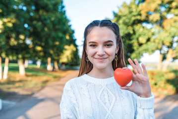 Happy cheerful teenage girl 13-15 years old, summer autumn spring in park, red heart in her hand....
