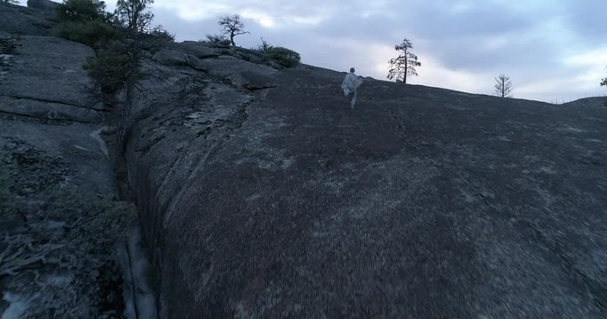 drone flight after running to peak man on rock cliff at Yosemite National Park, 4k