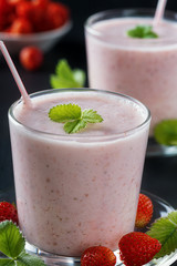  Strawberry smoothie or milkshake in glass cup on black rustic background, healthy food for breakfast and snack