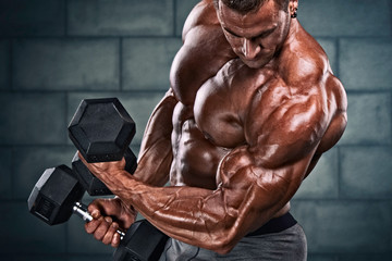 Strong Handsome Bodybuilder Exercising With Dumbbells. Copy Space