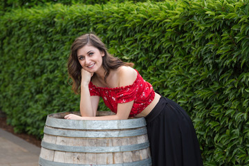 Young brunette woman in a summer dress on a wooden wine barrel.