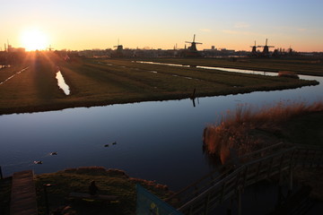 romantic sunset in red and yellow colors. the plain of the rural countryside of zaanse schans with its typical Dutch mills