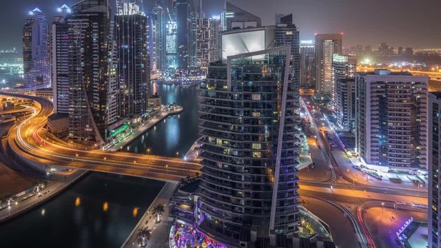 Aerial view of Dubai Marina residential and office skyscrapers with waterfront during all night timelapse with blinking lights turning off. Floating boats and yachts