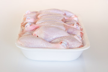 Uncooked chicken drumsticks in a styrofoam container