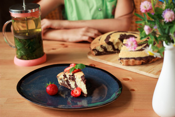 Homemade chocolate zebra cake with strawberries on dark blue plate on wooden table