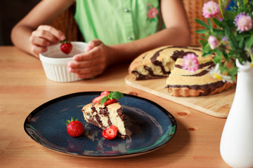 Homemade chocolate zebra cake with strawberries on dark blue plate on wooden table