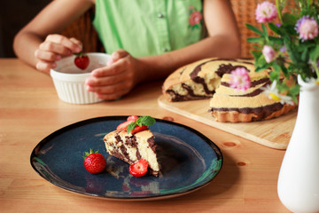 Homemade chocolate zebra cake with strawberries on dark blue plate on wooden table