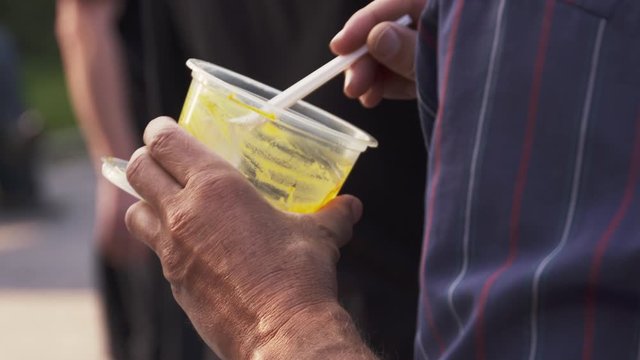 Hungry homeless man finishing a bowl of leftover soup, closeup