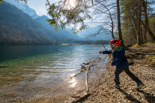 5 year old boy throwing stones into the crystal clear water of the Vorderer Langbathsee near Ebensee, Ober&ouml;sterreich, Austria