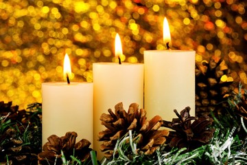 Brightly lit Christmas candles, snow-covered spruce Winter branch and cones. Candle light is a symbol of faith, hope, love, elegant creative design. Background glitter bokeh lights, New year holiday.