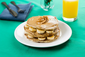 Pancakes with peanut butter and sliced bananas. Served with orange juice.