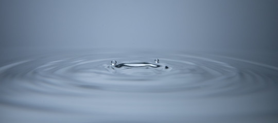 Droplets on water with ripples moving outward in concentric circles