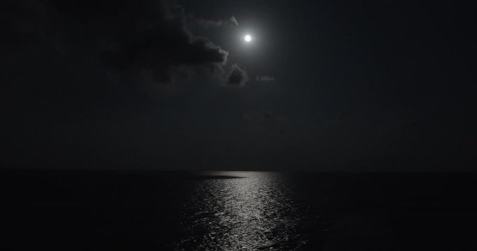 Full moon illuminates the ocean water while sailing