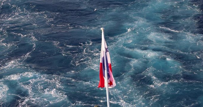 Panama flag waving in the wind with ocean water in the background.