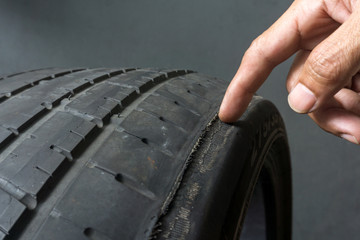 Finger pointing to damage on tire tread. Tire tread problems by tire pressure improper, Wheel...