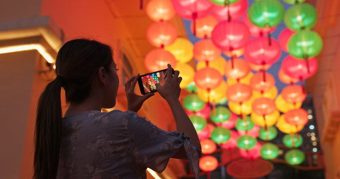 Woman take photo on cellphone with the chinese style lantern at night