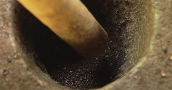 Close up shot of pestle blending fresh roasted coffee beans in mortar 4k footage