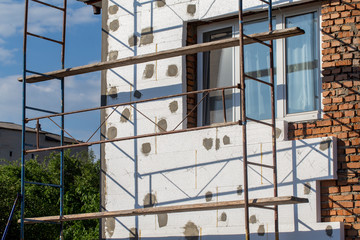 Scaffold on house, renovation. House for renovation with the scaffolding for workers on building