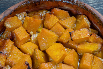 Baked yellow pumpkin with honey, olive oil and spices on a plate on the wooden table. Vegetarian food. Closeup