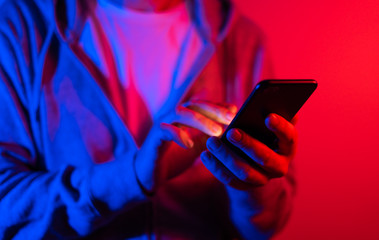 Male hand with smartphone. Finger typing on screen. Neon light