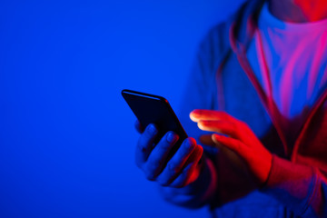 Male hand with smartphone. Finger typing on screen. Neon light
