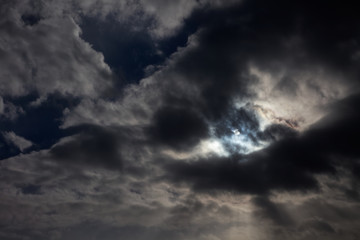 The sun is visible and hidden from between clouds