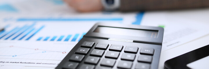 Obraz premium Black calculator and financial statistics on clipboard pad at office table closeup. Internal Revenue Service inspector sum check irs investigation earnings savings loan and credit concept