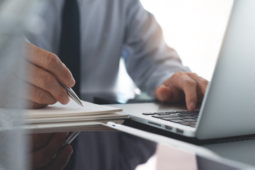 Businessman working on laptop computer on glass table in office