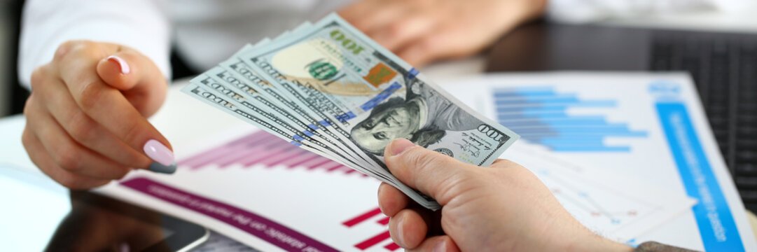 Male arm pay bunch of hundred dollars bills to office clerk closeup. Bribery accept backhander banknote venality laundering back scheme offshore company irs kickback collusion lobby gift compensation