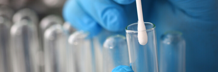 Forensic scientist conducting criminal investigation aganist laboratory background. Holds cotton...
