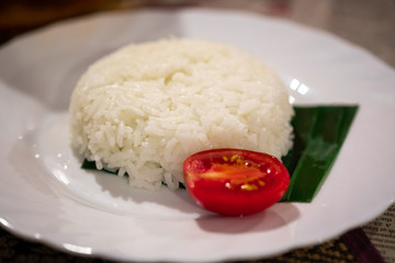 A plate of national Thai dishes with rice and tomatoes closeup on the table.