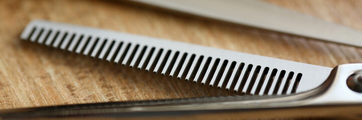 Thinning shears lie on wooden table in hair salon closeup. Stylish hairstyle concept background.