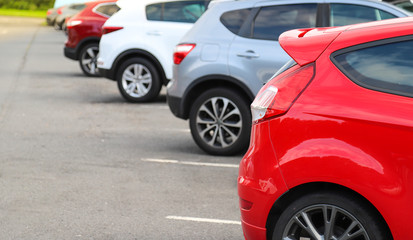 Fototapeta premium Closeup of rear, back side of red car with other cars parking in outdoor parking area.