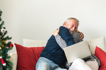 Fototapeta premium Christmas online shopping. Senior caucasian man and woman sitting on couch using laptop in living room. Winning mood.