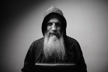 Portrait of mature bald bearded man wearing hoodie in black and white