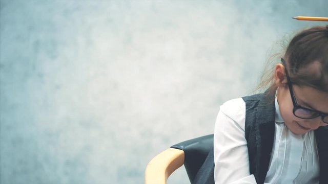 Close-up of a small business girl sitting on a chair on a gray background. During this, he speaks by phone and smiles.