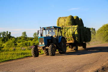 tractor driven fresh hay rolled, after seasonal harvesting