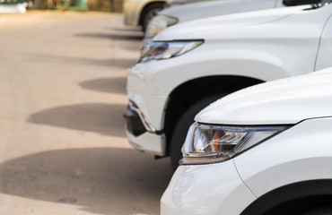Fototapeta premium Closeup of front side of white car in outdoor parking area with bright sunlight. 