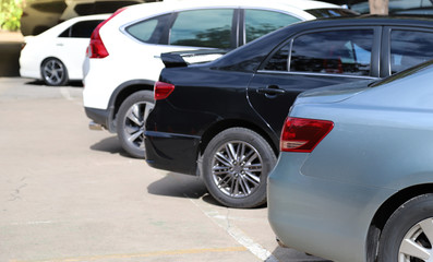 Closeup of rear side of soft blue car with  other cars parking in outdoor parking area under bright sunlight. 
