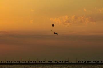 a man flying at the sunset holding uae flag, uae flag waving at the sunset, Flying paraglider with uae flag , uae flag day. united arab emirates 