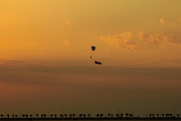 a man flying at the sunset holding uae flag, uae flag waving at the sunset, Flying paraglider with uae flag , uae flag day. united arab emirates 