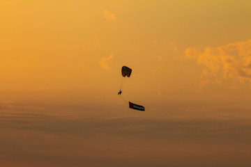 a man flying at the sunset holding uae flag, uae flag waving at the sunset, Flying paraglider with uae flag , uae flag day. united arab emirates 