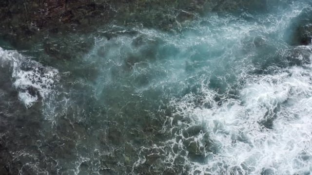 Top down abstract aerial view of ocean waves crashing on tropical coral reef