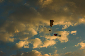 a man flying at the sunset holding uae flag, uae flag waving at the sunset, Flying paraglider with uae flag , uae flag day. united arab emirates 